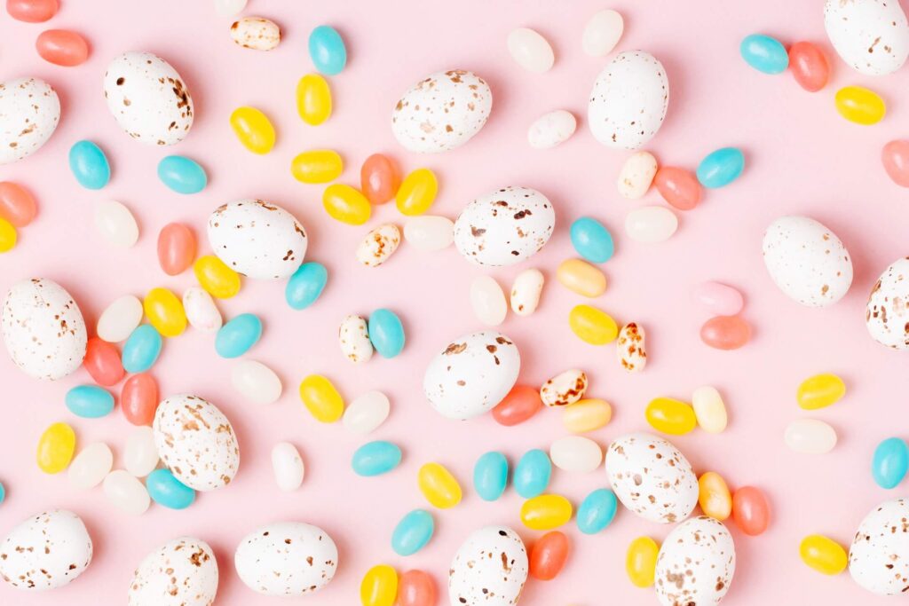 Jelly beans and easter candy malt eggs with a pink background.